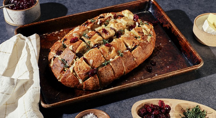 Cooked loaf of cranberry and brie pull-apart bread in weathered metal cooking pan