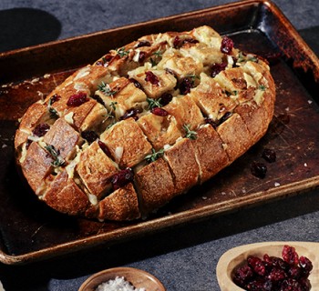Cooked loaf of cranberry and brie pull-apart bread in weathered metal cooking pan
