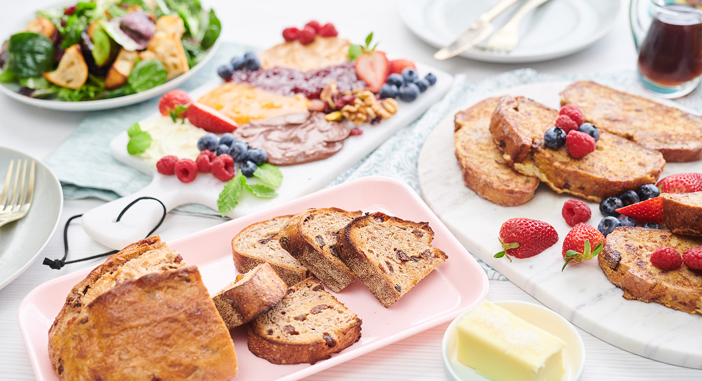 Brunch spread of Artisan bread, sliced with butter, fruit and dinner wear on pastel plates