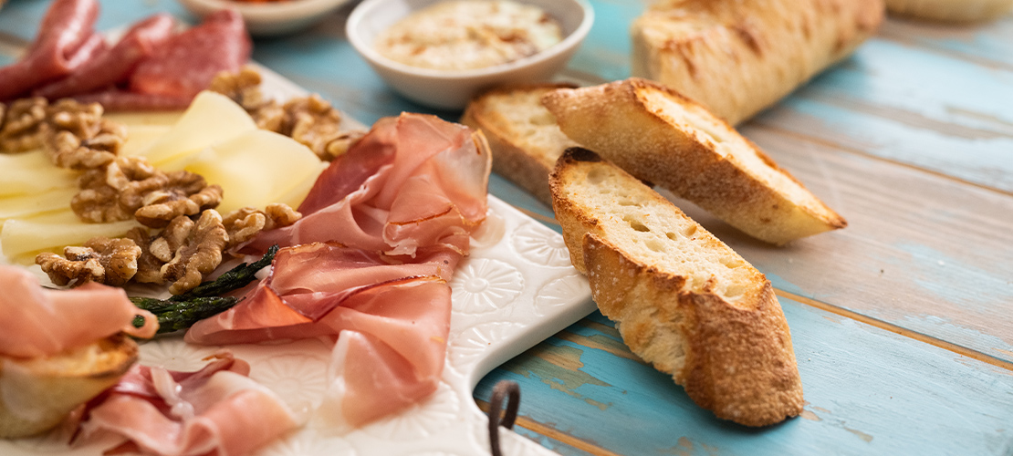 Close-up of a charcuterie board with assorted meat, bread, cheese, nuts, and dip