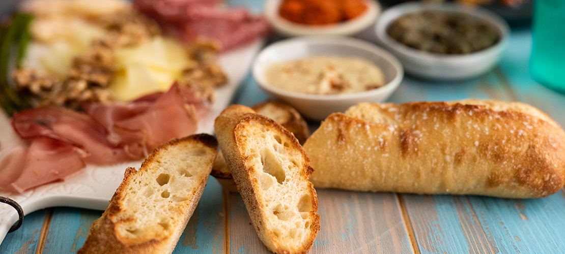 Close-up of baguettes with charcuterie board and dips in the background