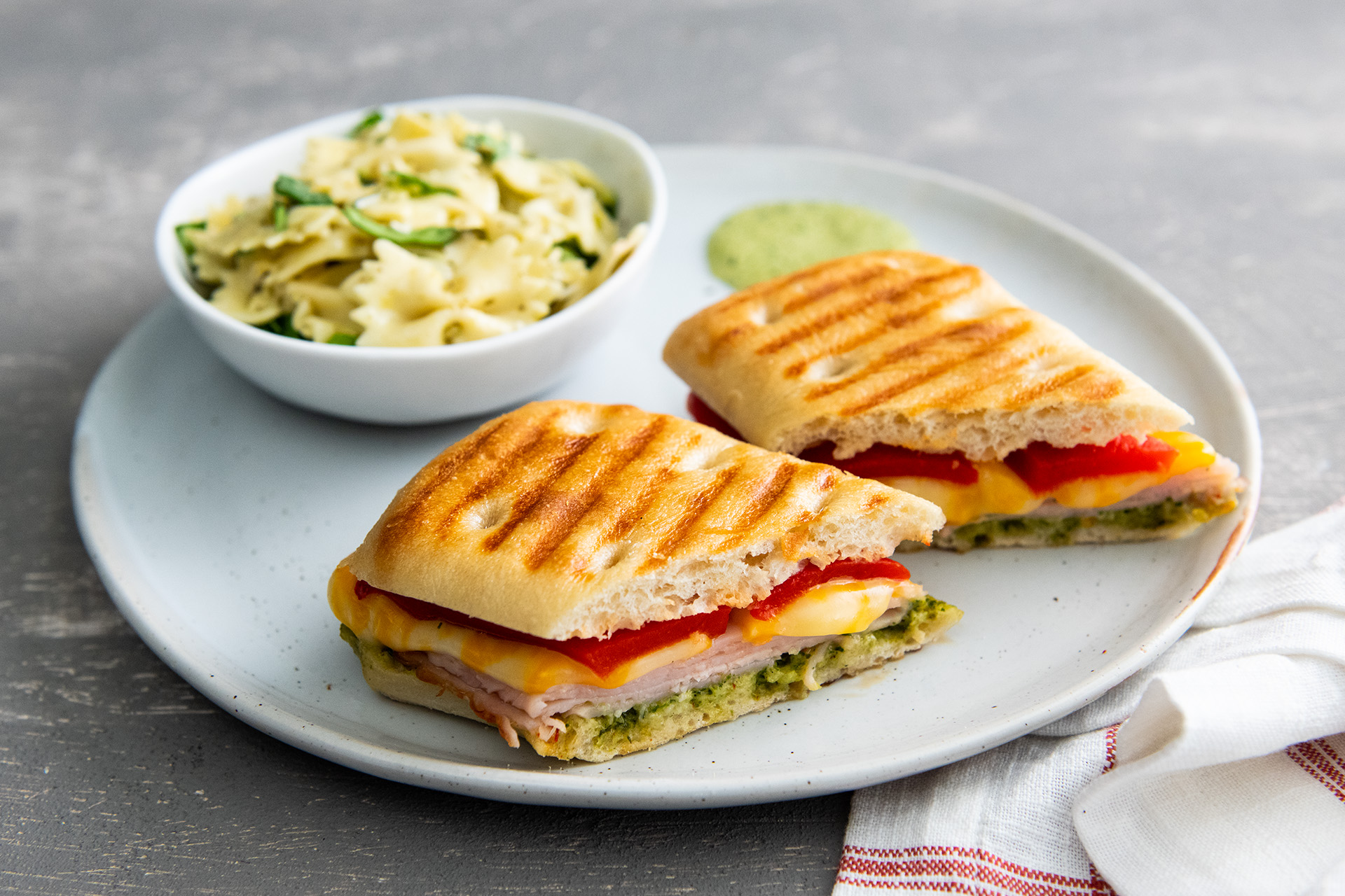 SlicedFocaccia Turkey Pesto Aioli Panini Sandwich on white plate