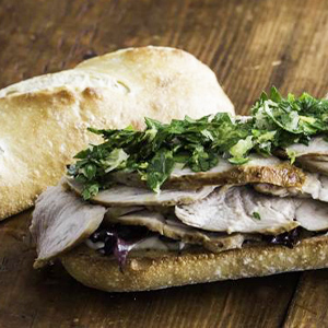 Porchetta and broccoli rabe sandwich on a French baguette served open-face