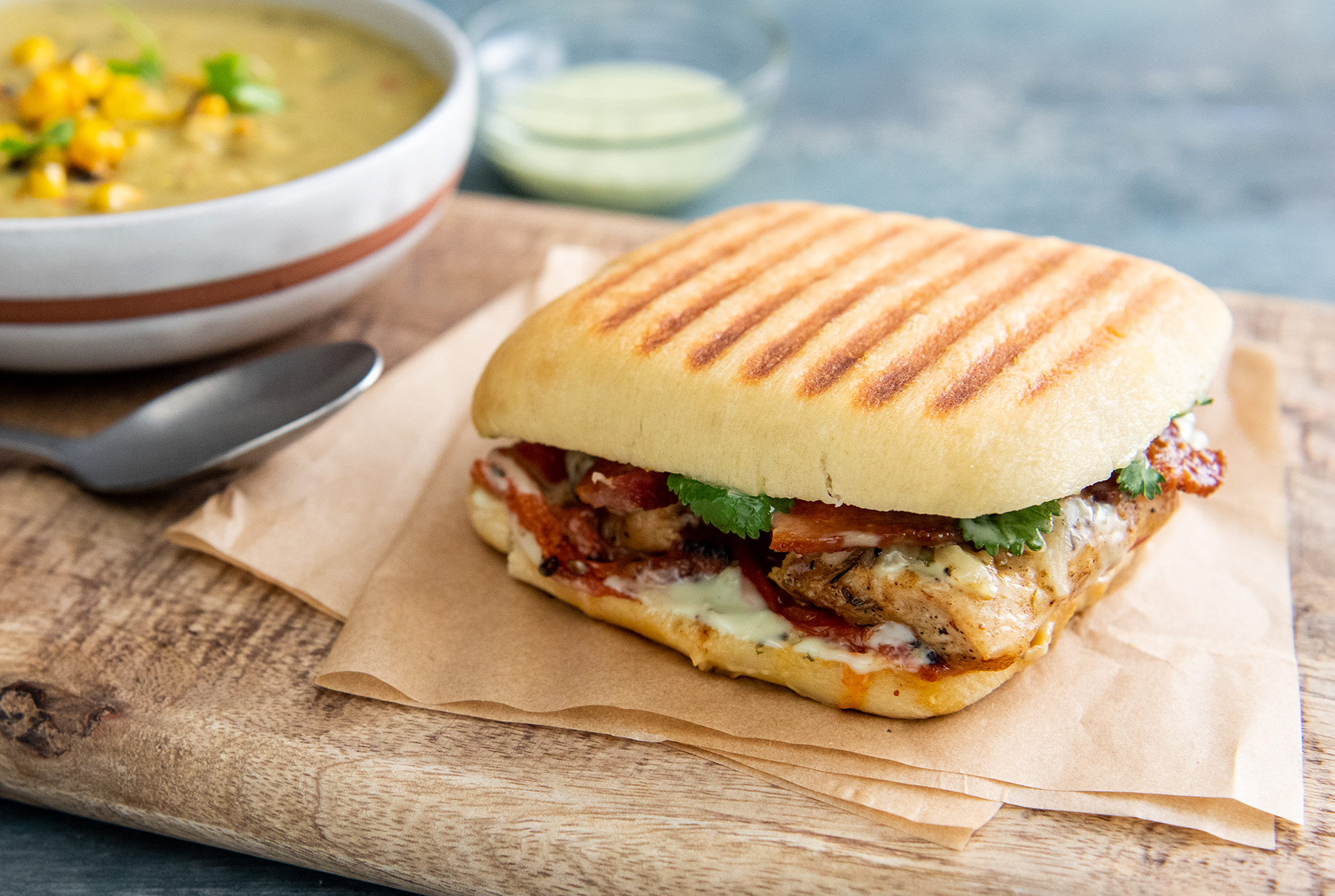 Whole Ciabatta Grilled Chicken Panini with Honey-Lime Dressing sitting on wood serving board
