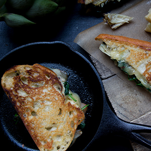 Sautéed spinach and artichoke Swiss grilled cheese sandwich on Tuscan Loaf in a skillet