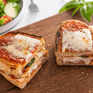 Chicken parm grilled cheese with fontina and Italian Round slices on a wood tray