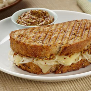 Grilled cheese sandwich made with marinated onions, gruyere, and Country White Sourdough Loaf on a plate with whole grain mustard on the side