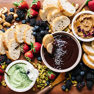 Dark chocolate, matcha jasmine mascarpone and salted honey cashew dips plated with assorted berries and slices of French Baguette