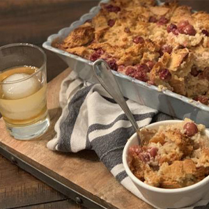 Bourbon-soaked cherry bread pudding in a large dish with a single serving on the side