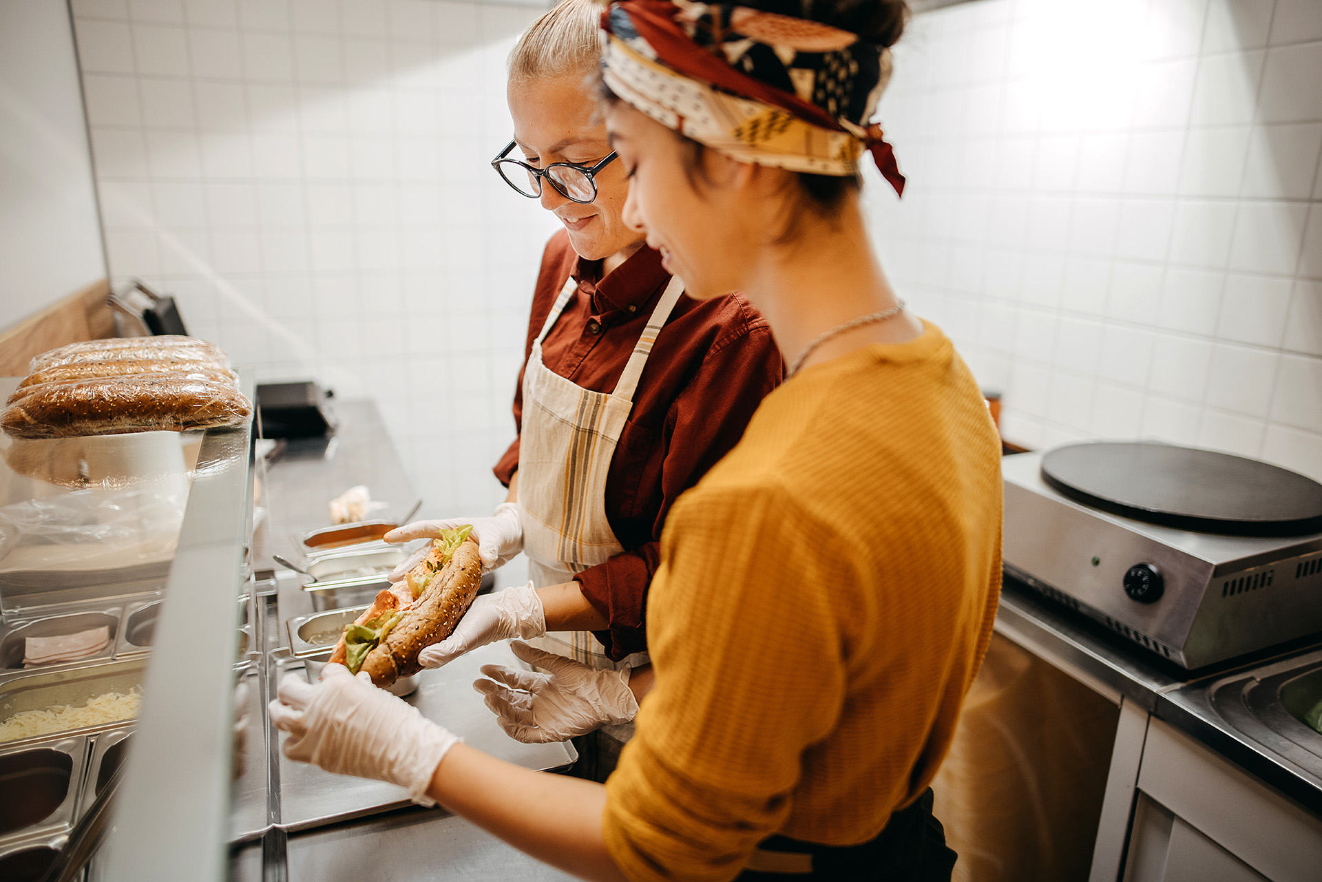Two chefs making custom sandwich with artisan bread in a commercial kitchen