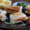 Platter of French Baguette sandwiches with a bowl of chips and pickles