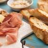 Close-up of a charcuterie board with assorted meat, bread, cheese, nuts, and dip
