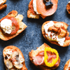 Assorted toasted bread topped with pepperoni, prosciutto, peppers and cheese