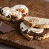 Two s'mores sourdough sandwiches laying on old distressed wood cutting board