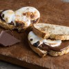 Two s'mores sourdough sandwiches laying on old distressed wood cutting board