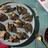 12 Semolina cheese stuffing balls plated on a slate colored serving dish sitting on a green tile counter top with red napkins