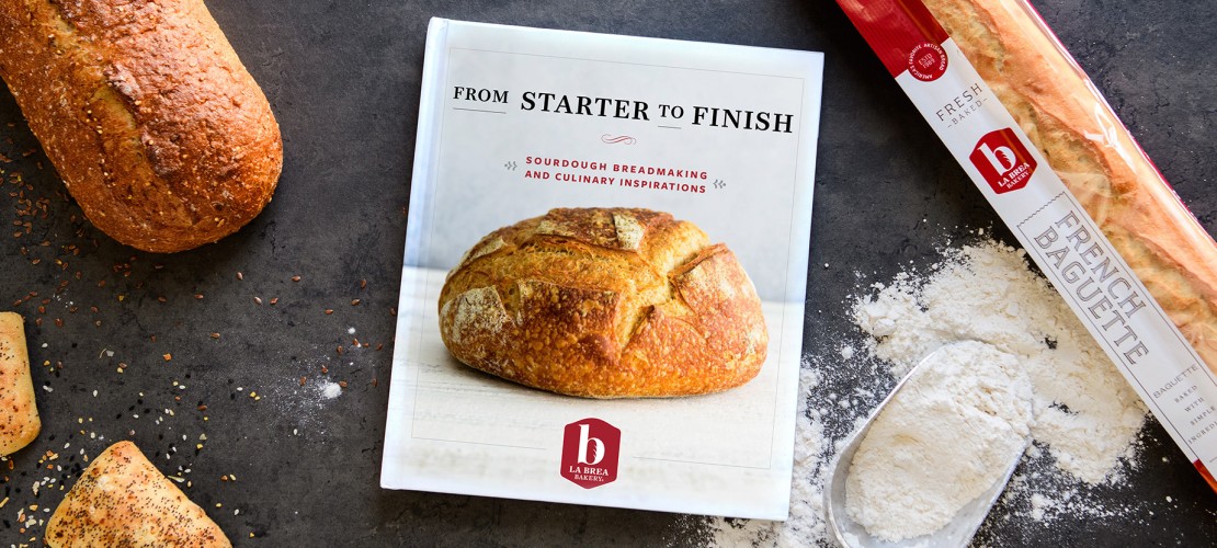 Cookbook laying on table with flour and artisan breads