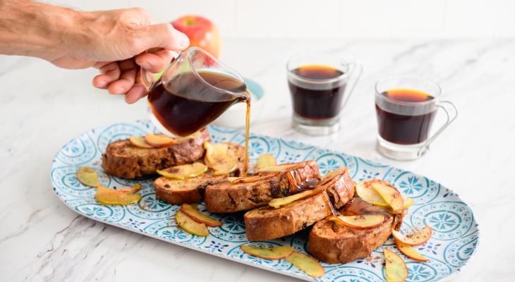 Hand pouring syrup over Cinnamon Raisin French Toast