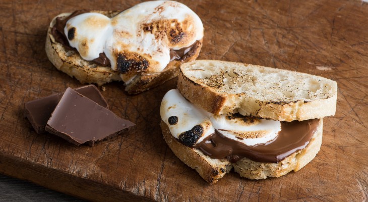 Two s'mores sourdough sandwiches laying on old distressed wood cutting board