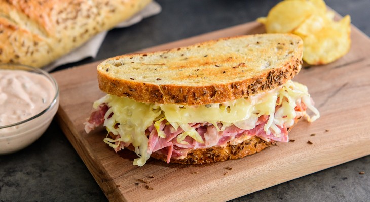 Reuben sandwich with New York rye artisan bread on wooden cutting board