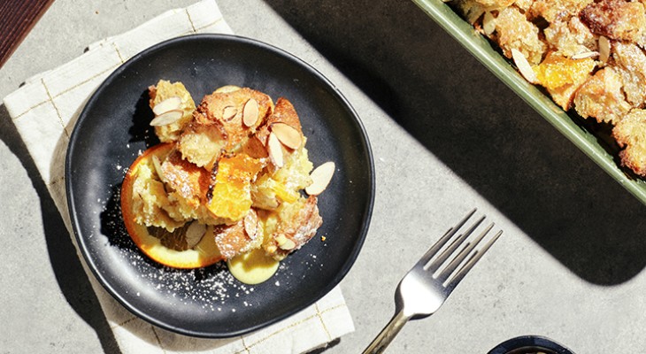 Serving of Creme brulee bake with sourdough loaf croutons on a black plate with silverware