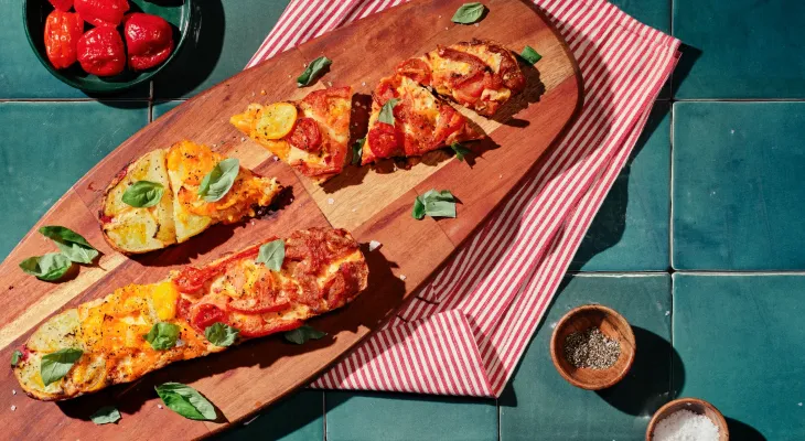 Tomato pie baguette pizza on a wood serving board with a pack of La Brea Take and bake baguette artisan bread