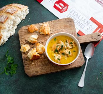  Bowl of Sweet Potato & Sage Soup with Croutons on a Wooden Board and a slice of Italian Round Loaf