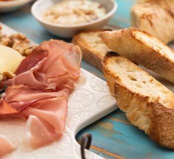 Close-up of a charcuterie board with assorted meat, bread, cheese, nuts, and dip