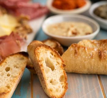 Close-up of baguettes with charcuterie board and dips in the background