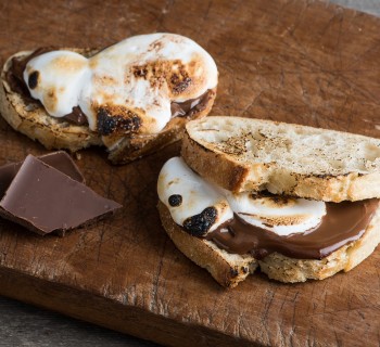 Two s'mores sourdough sandwiches laying on old distressed wood cutting board