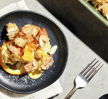 Serving of Creme brulee bake with sourdough loaf croutons on a black plate with silverware