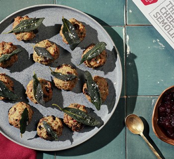 12 Semolina cheese stuffing balls plated on a slate colored serving dish sitting on a green tile counter top with red napkins