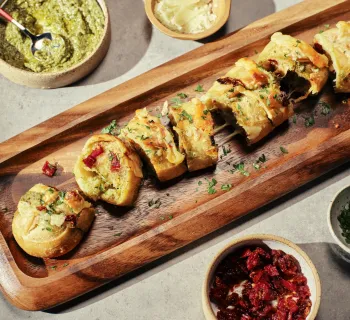 Sliced loaf of La Brea artisan bread with toppings in bowls